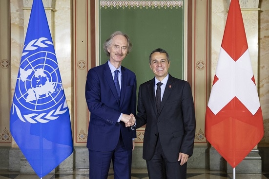 Bundesrat Cassis und Geir Pedersen schütteln sich in Bern die Hand. Im Hintergrund sind die Flaggen der Schweiz und der UNO zu sehen.