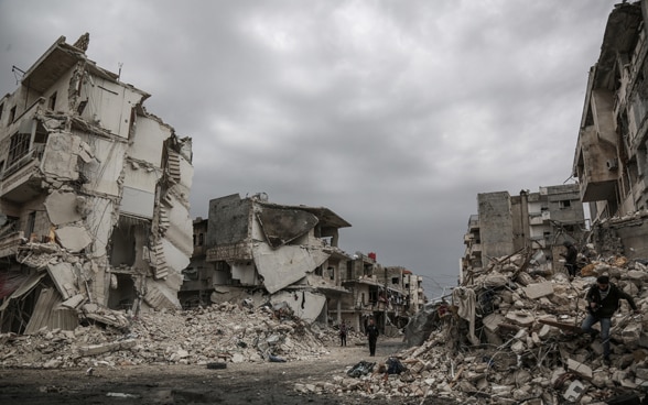 Des gens marchent à travers les ruines de la ville syrienne d'Idlib, qui a été frappée par des raids aériens.