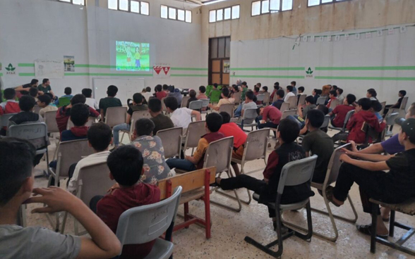 Bambini siriani guardano un cartone animato in una sala.