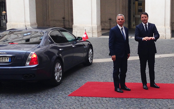 Didier Burkhalter e Matteo Renzi in piedi accanto a un’automobile nera.