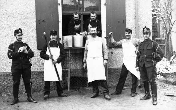 Scatto in bianco e nero di un gruppo di soldati e cuochi di campo dell’Esercito svizzero durante la prima guerra mondiale. © Keystone 