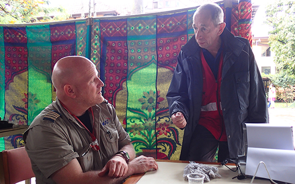 A member of the Swiss Humanitarian Aid rapid response team talking with an NGO representative.
