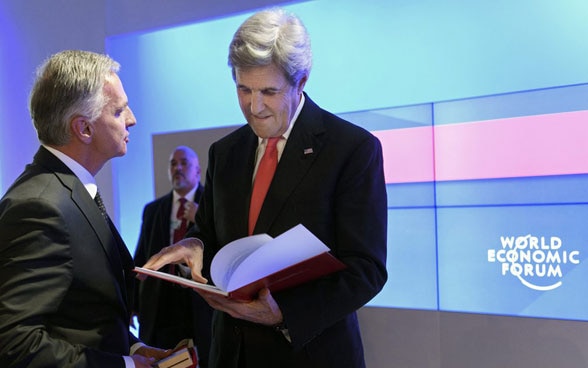 Didier Burkhalter überreicht US-Aussenminister John Kerry am WEF 2017 eine Sammlung von diplomatischen Dokumenten der Schweiz aus der Zeit des Schweizer Schutzmachtmandats USA–Kuba.  