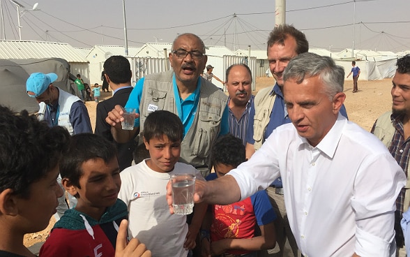 Didier Burkhalter shares a glass of water with the childrens of the Azraq refugee camp