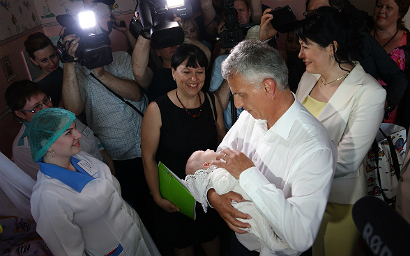 Dider Burkhalter holds a newborn baby in his arms.