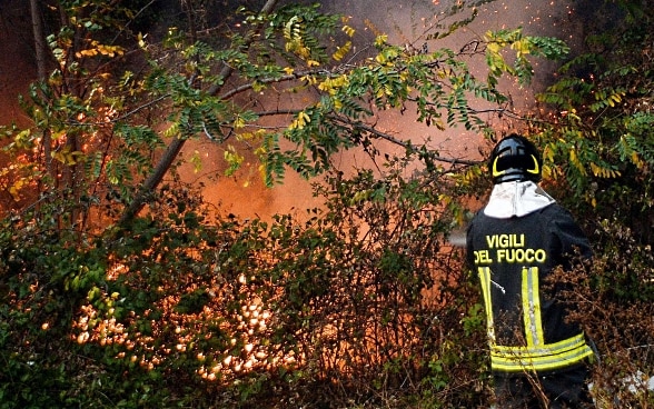 Un pompier italien éteint avec la lance des foyer de feu.