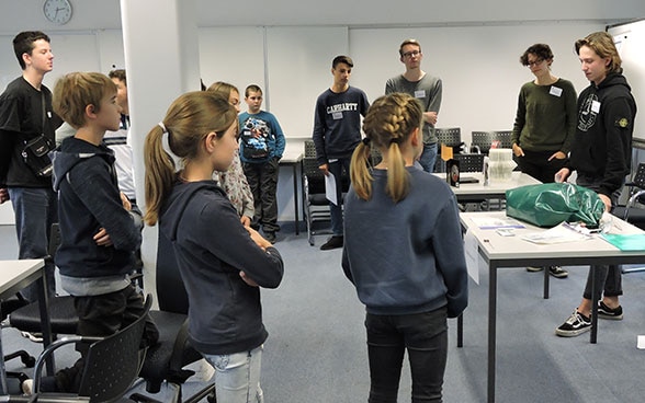 A group of children listen to FDFA employees describing their work. 