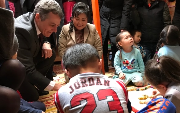 Bundesrat Cassis spielt mit mongolischen Kindern in einer Schule.