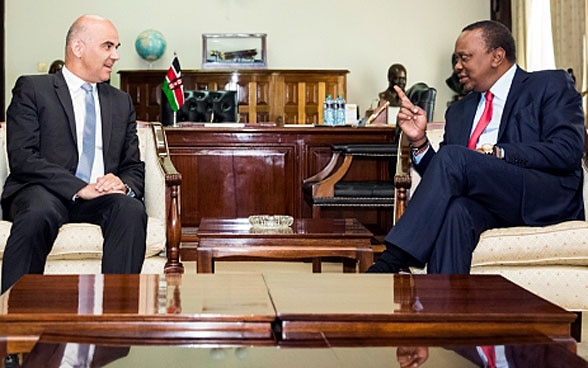 Il presidente della Confederazione Berset e il presidente keniota Kenyatta siedono a un tavolo di legno e discutono.