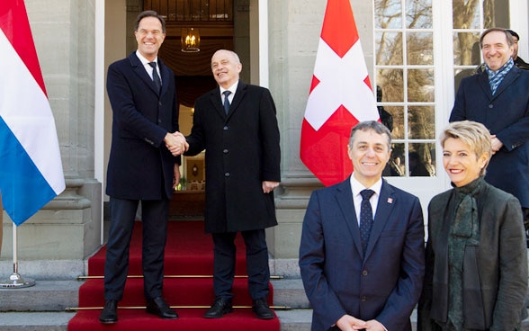 Le Premier ministre néerlandais Mark Rutte (centre-gauche) et Ueli Maurer, président de la Confédération suisse (centre-droite) se serrent la main en présence du conseiller fédéral Ignazio Cassis (troisième à droite) et de la conseillère fédérale Karin Keller-Sutter (deuxième à droite) avant leur réunion à la résidence du Lohn.