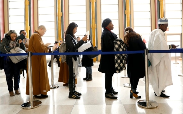 Women and men are waiting for registration in a high hall. 