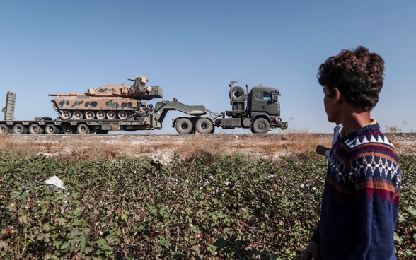Ein Arbeiter in einem Baumwollfeld in der Region Sanliurfa beobachtet einen türkischen Militärtransport auf dem Weg in den Nordosten Syriens