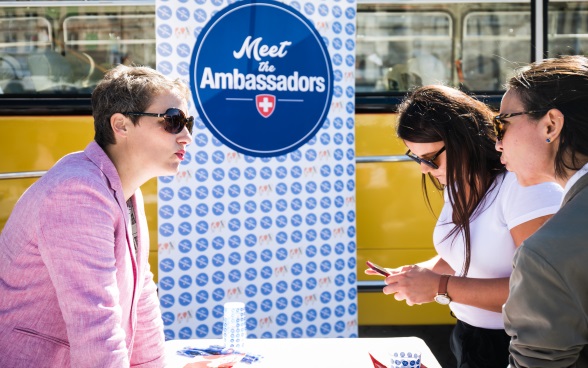 Une ambassadrice discute avec deux visiteurs 