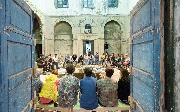 Un groupe de jeunes est assis en cercle dans la cour intérieur d’un bâtiment, à l’occasion du festival Dream City à Tunis.