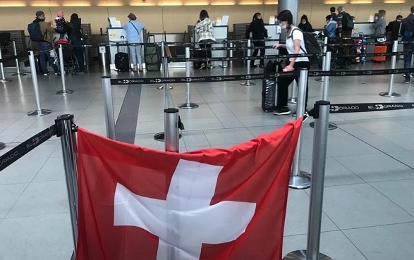 In der Halle des Flughafens von Bogotà hängt eine Schweizer Fahne beim Check-in-Schalter für den Flug in die Schweiz.