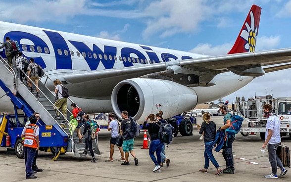 A plane, in front of it the flight stairs, through which a number of passengers board.