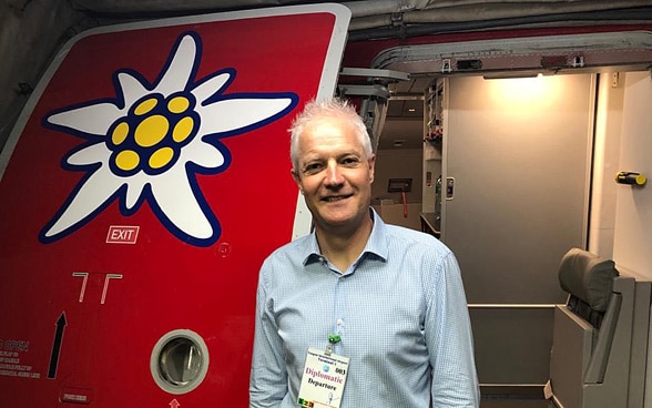 The Swiss ambassador to Myanmar, Tim Enderlin, is standing at the door of the Edelweiss aircraft in Yangon. An edelweiss flower is painted on the door.