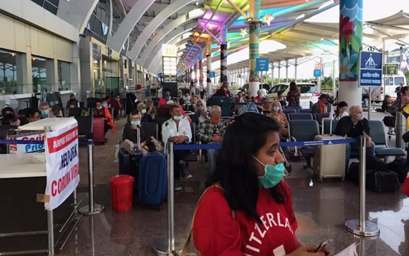 Passengers for the Goa-Zurich flight are waiting in the lobby of the Goa airport. 