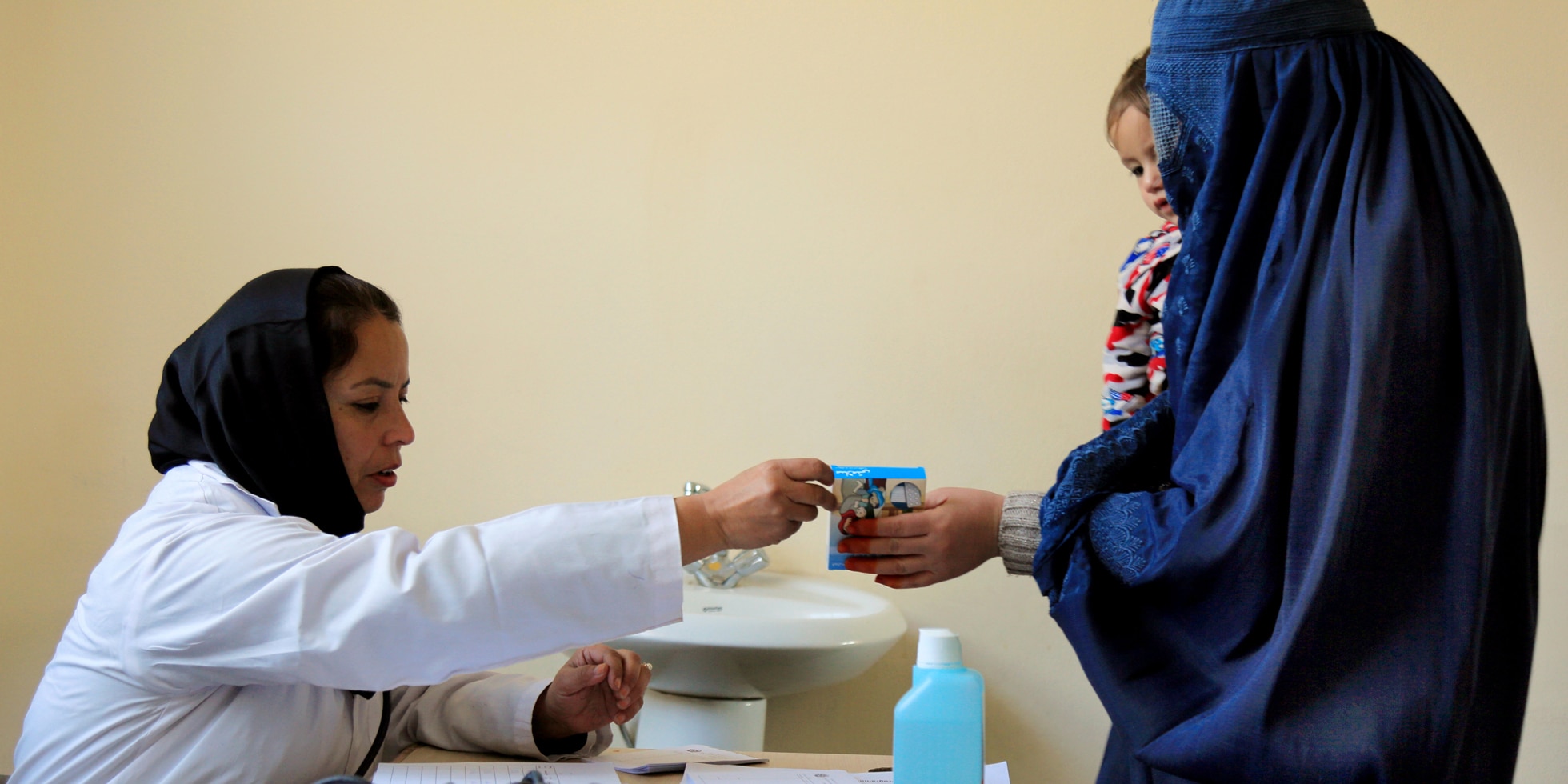   A mother with her child in her arms receives medication from a hospital employee in Kabul, Afghanistan. 