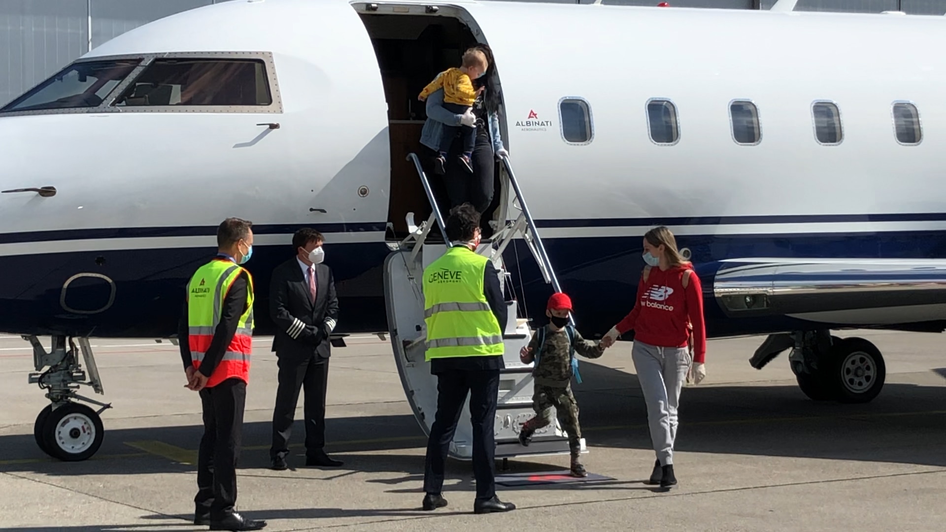 À l'aéroport de Genève, les adultes et les enfants montent d’un avion dans un bus.