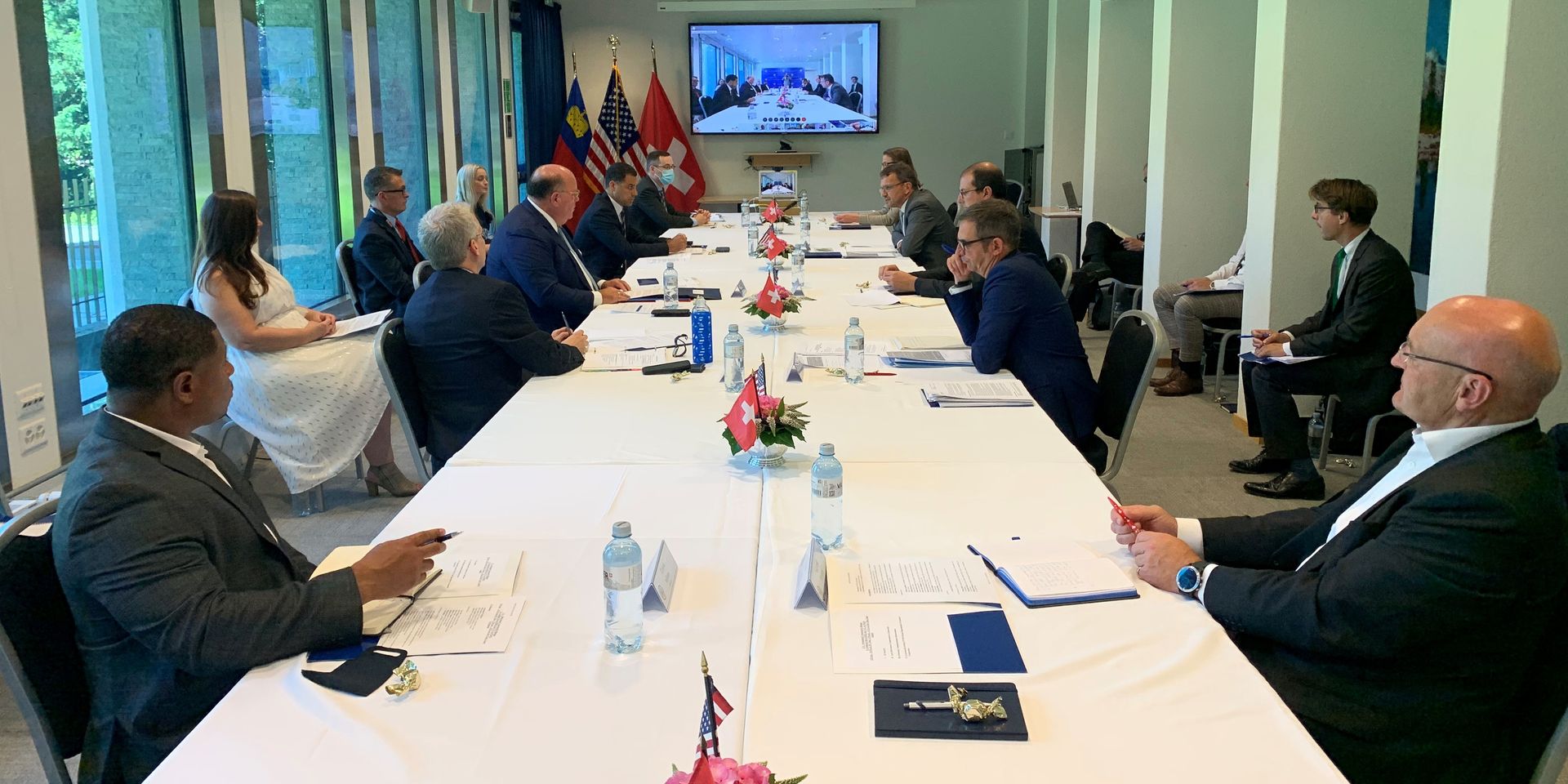 Several people at a conference table in Switzerland talk via video conference with colleagues in America.