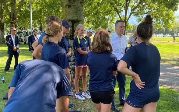 Federal Councillor Ignazio Cassis talks to track and field athletes outdoors. 