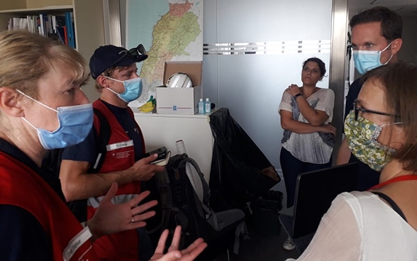 Des experts du Corps suisse d'aide humanitaire discutent, dans un bureau, des mesures à prendre.