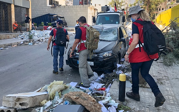 Des experts du Corps suisse d'aide humanitaire traversent une route pleine de débris.
