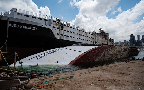 In the port of Beirut one side of a sunken ship can be seen in the water.