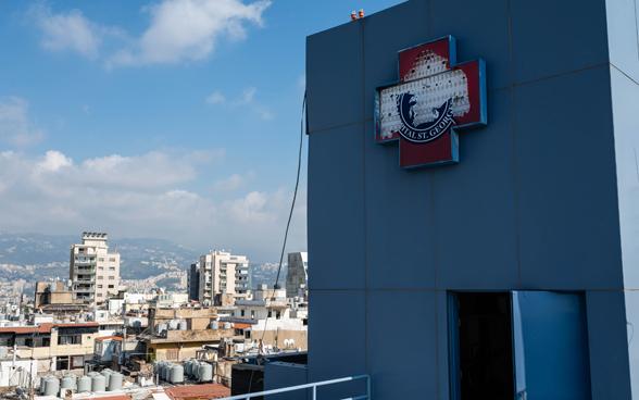 View of the exterior of a broken hospital. In the background you can see the consequences of the explosion on the city of Beirut.