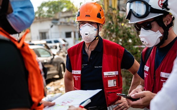 Ingenieurin Regina Wenk unterhält sich mit zwei Ingenieuren des Schweizerischen Korps für humanitäre Hilfe.