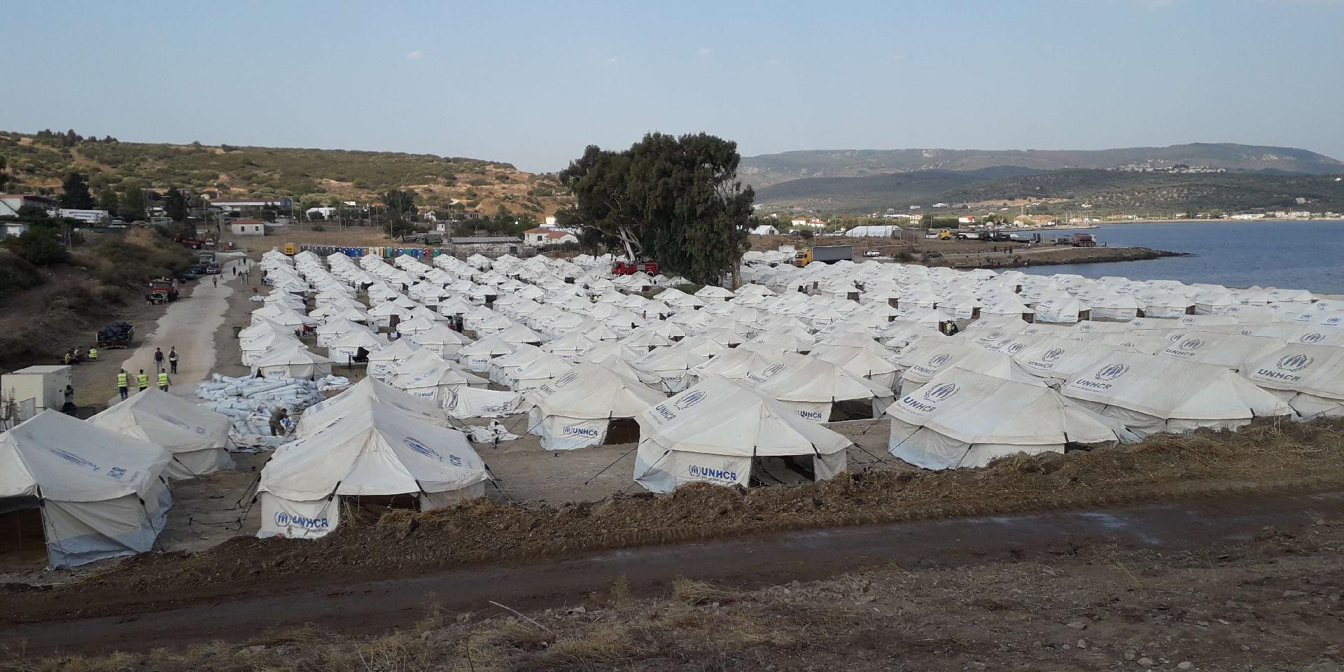 Numerous tents together form a camp right on the seashore of the island of Lesbos.