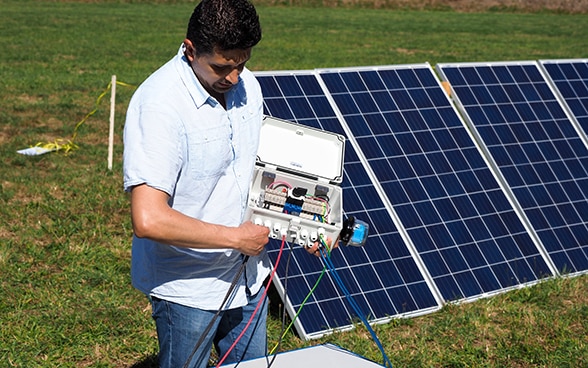 Un expert du Corps suisse d'aide humanitaire connecte des panneaux solaires.