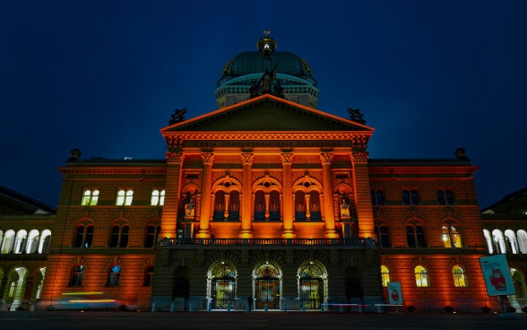 Das Bundeshaus erstrahlt in oranger Farbe.
