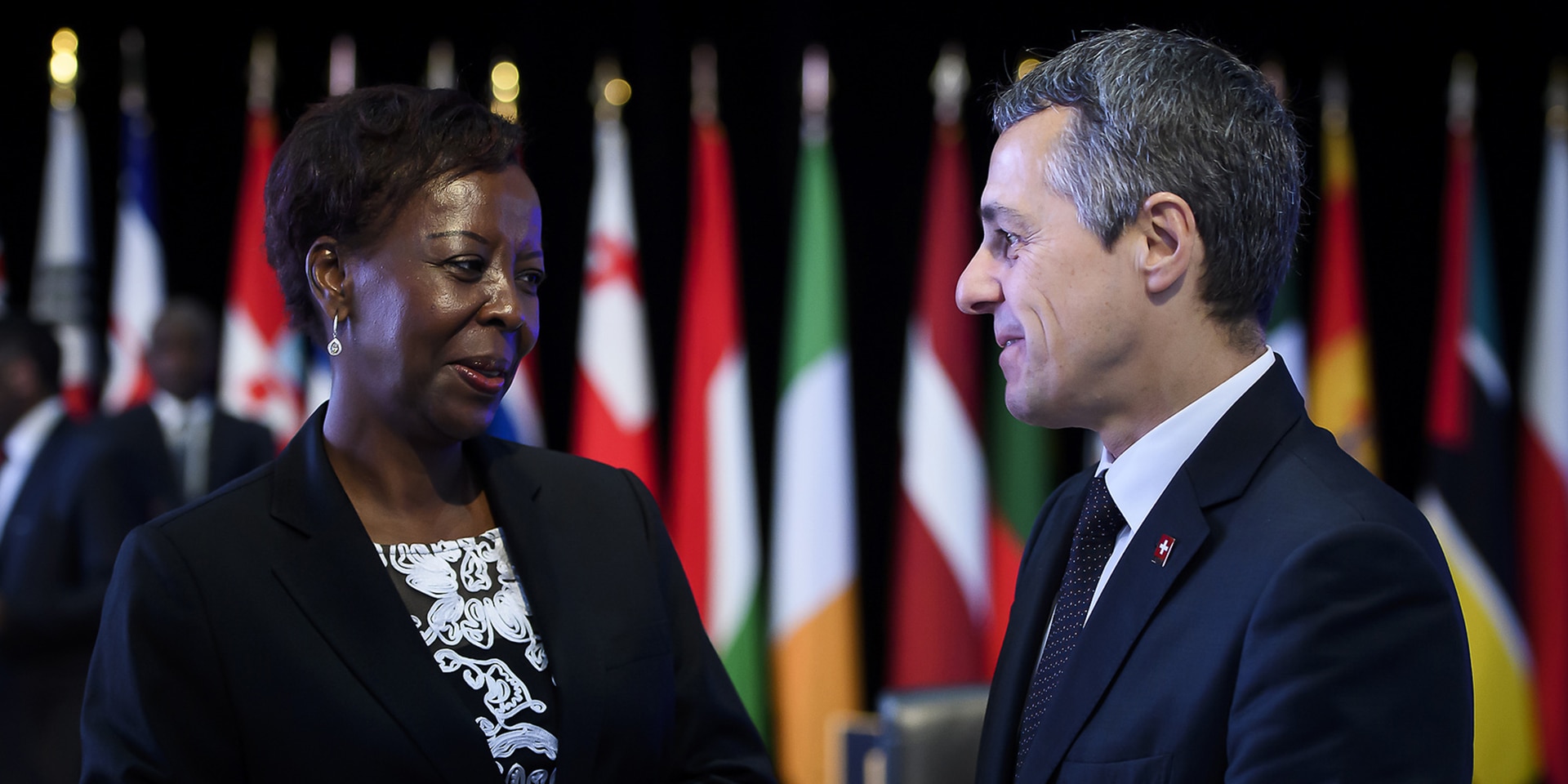 Ignazio Cassis und die Generalsekretärin der Frankophonie, Louise Mushikiwabo, im Gespräch. Im Hintergrund die Flaggen der 54 Mitgliedsstaaten und Regierungen.