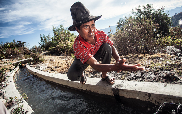  Homme accroupi près d’un canal d’irrigation