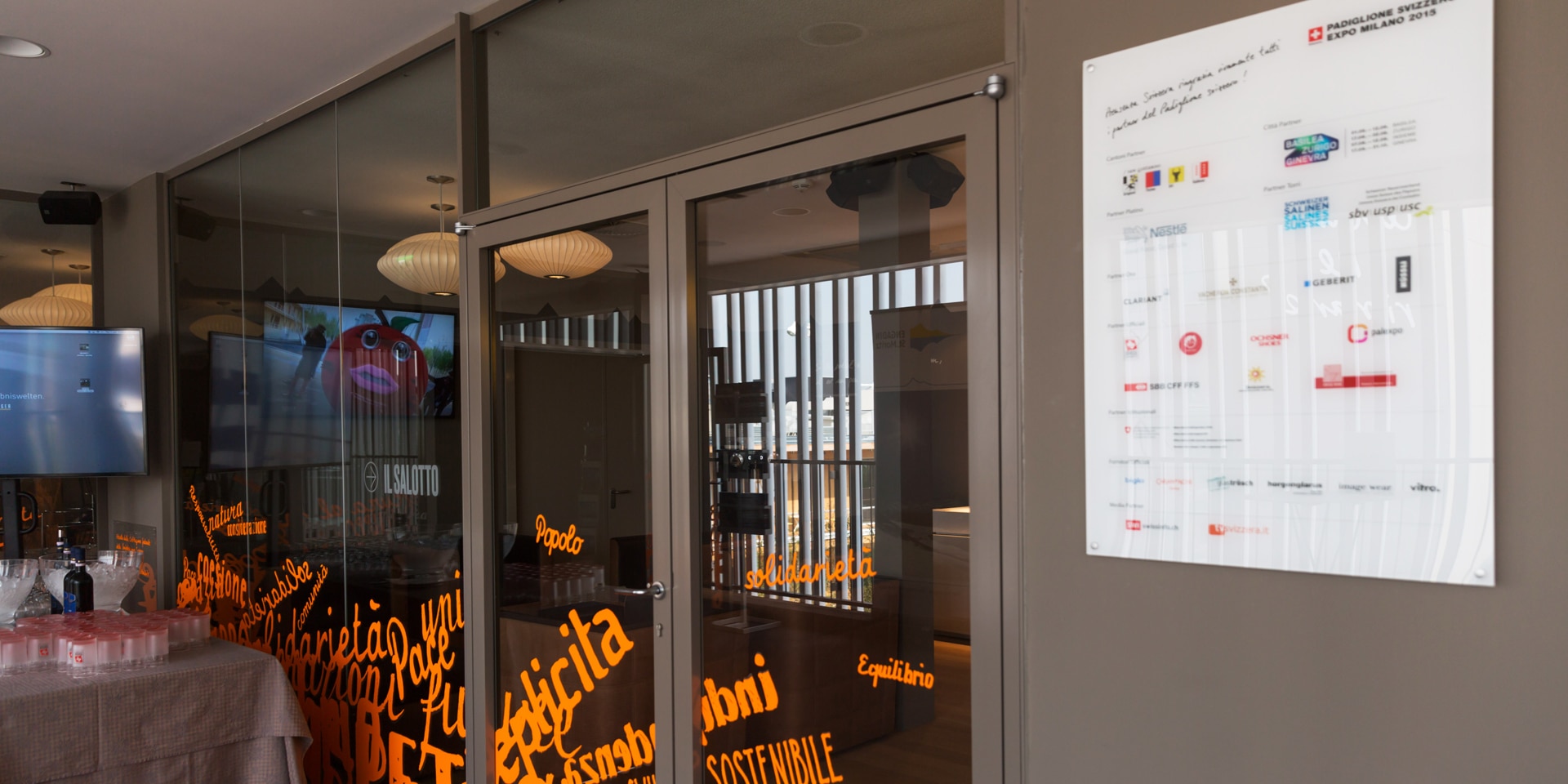 A white panel at the entrance to a building details all the partners of the Swiss pavilion at the 2015 World Expo in Milan.