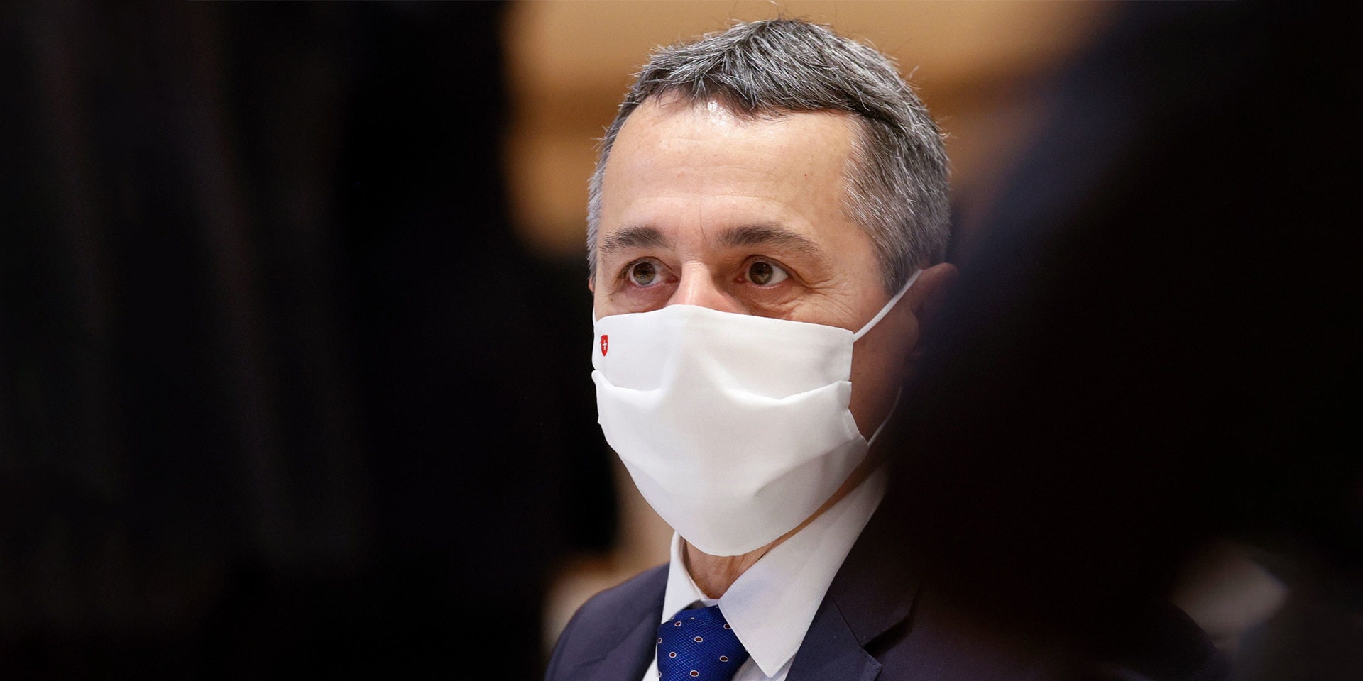  Gros plan sur le conseiller fédéral Ignazio Cassis, assis dans la salle, portant un masque avec une croix suisse, lors d’une réunion de l’ONU en novembre 2020.