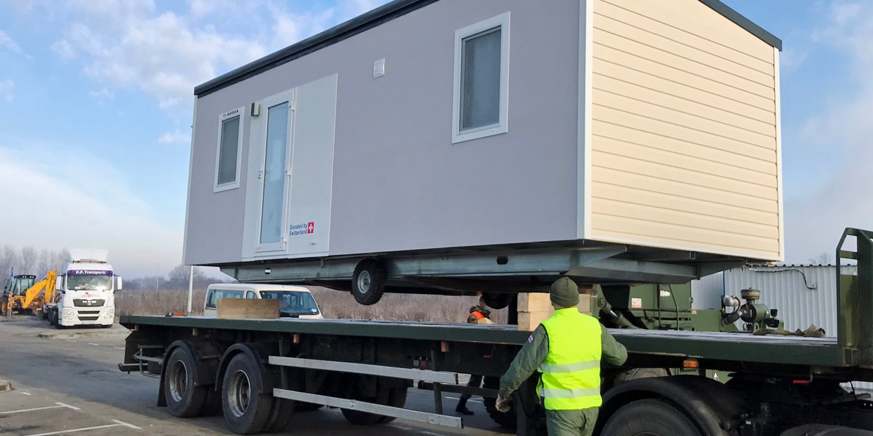 A mobile housing unit is transported by truck.