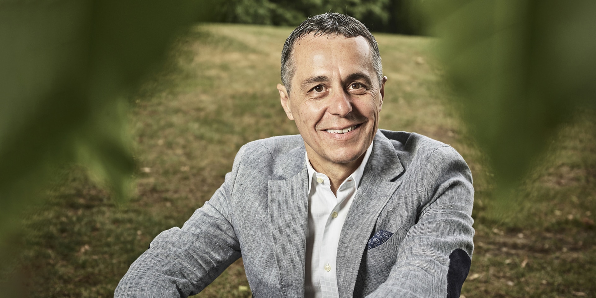 Immagine del consigliere federale Ignazio Cassis, seduto su un prato.