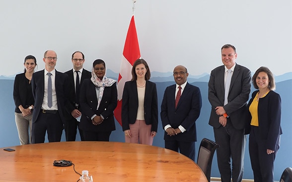  Alcuni membri del gruppo di preparazione svizzero e sudanese sono in piedi dietro un tavolo.