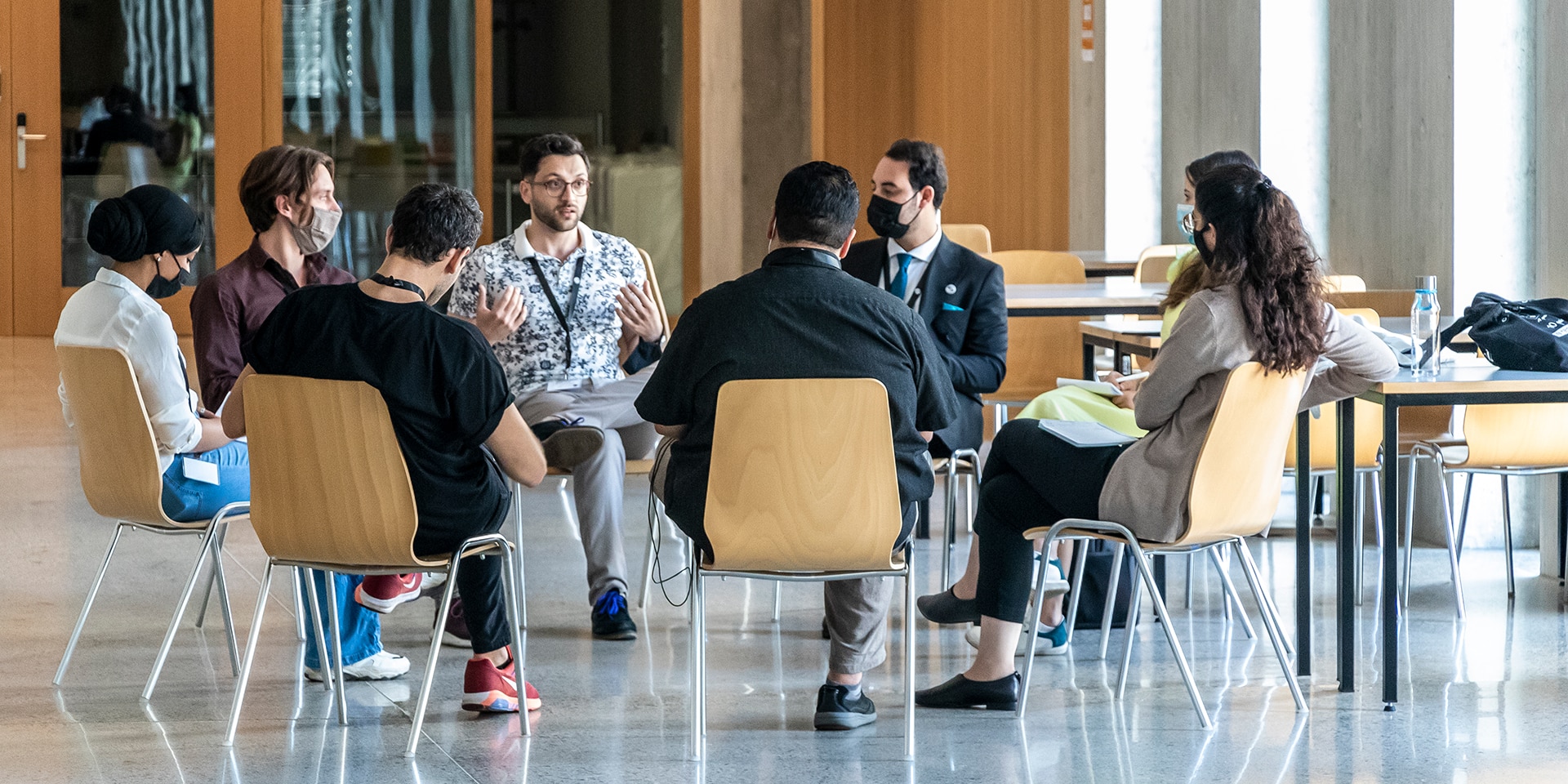 Einige Teilnehmer des MEM Summer Summit diskutieren, während sie auf Stühlen im Kreis sitzen.