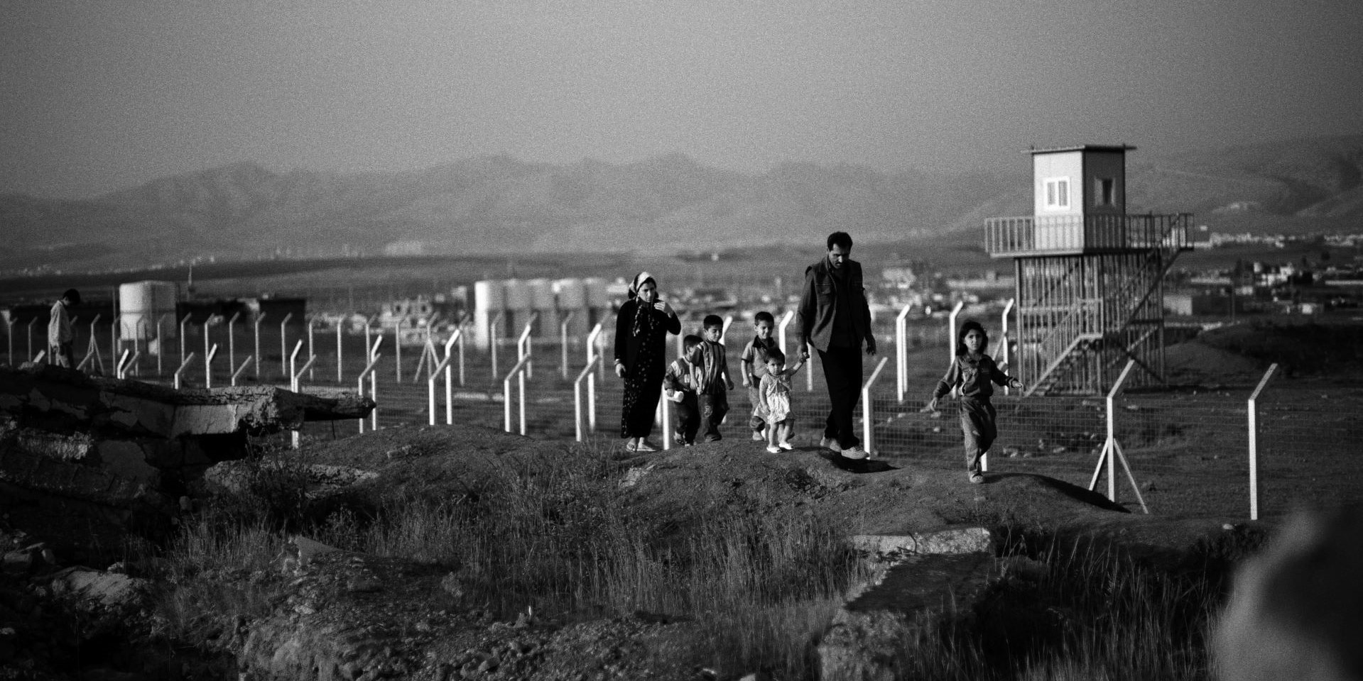 Una famiglia irachena passeggia in un campo devastato da munizioni a grappolo.