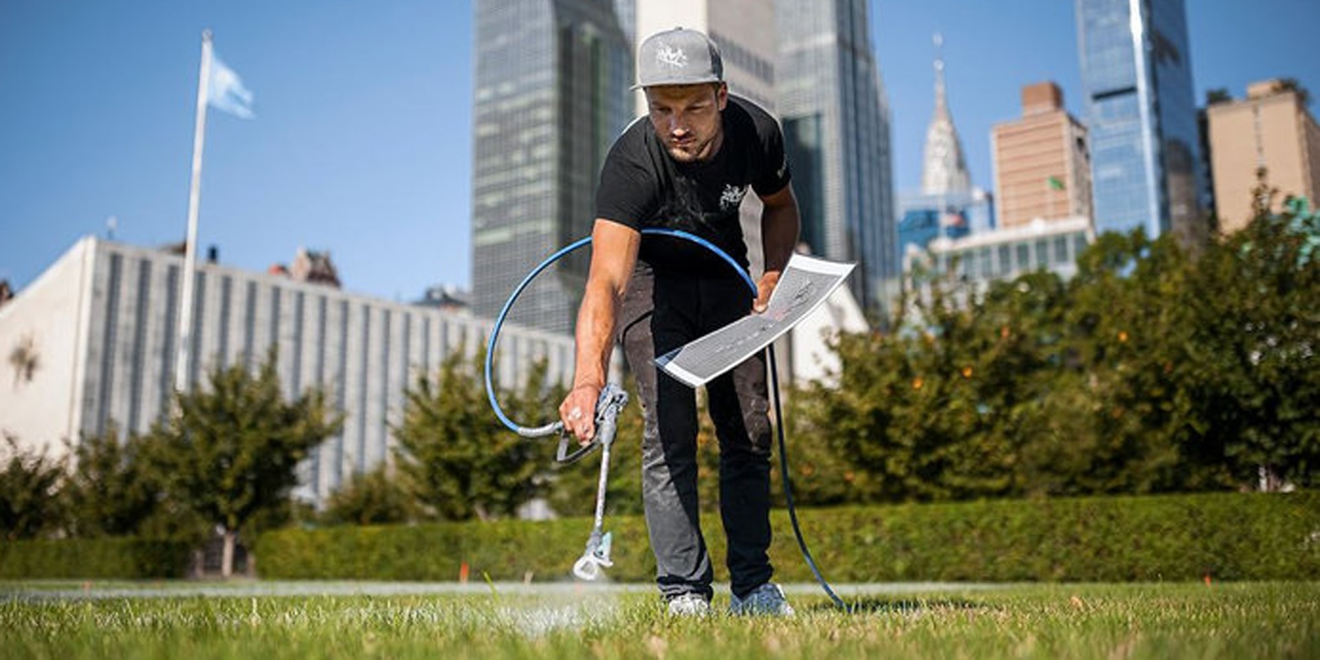 Un jeune homme crée une peinture sur l’herbe au milieu de New York.