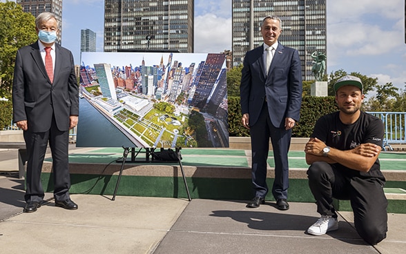 En présence de l'artiste Saype (à droite), le conseiller fédéral Ignazio Cassis (debout au milieu) remet au secrétaire général de l'ONU António Guterres (debout à gauche), une photo de l'immense fresque représentant deux enfants dessinant leur monde de demain.