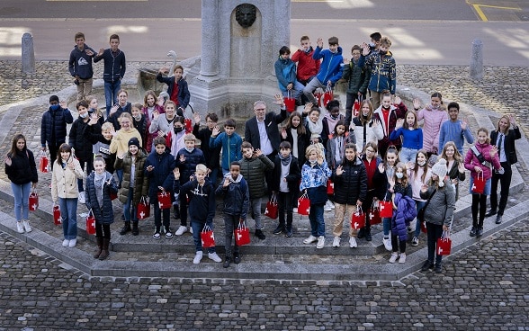 FDFA Secretary-General Markus Seiler poses with the 50 children in front of the Federal Palace.