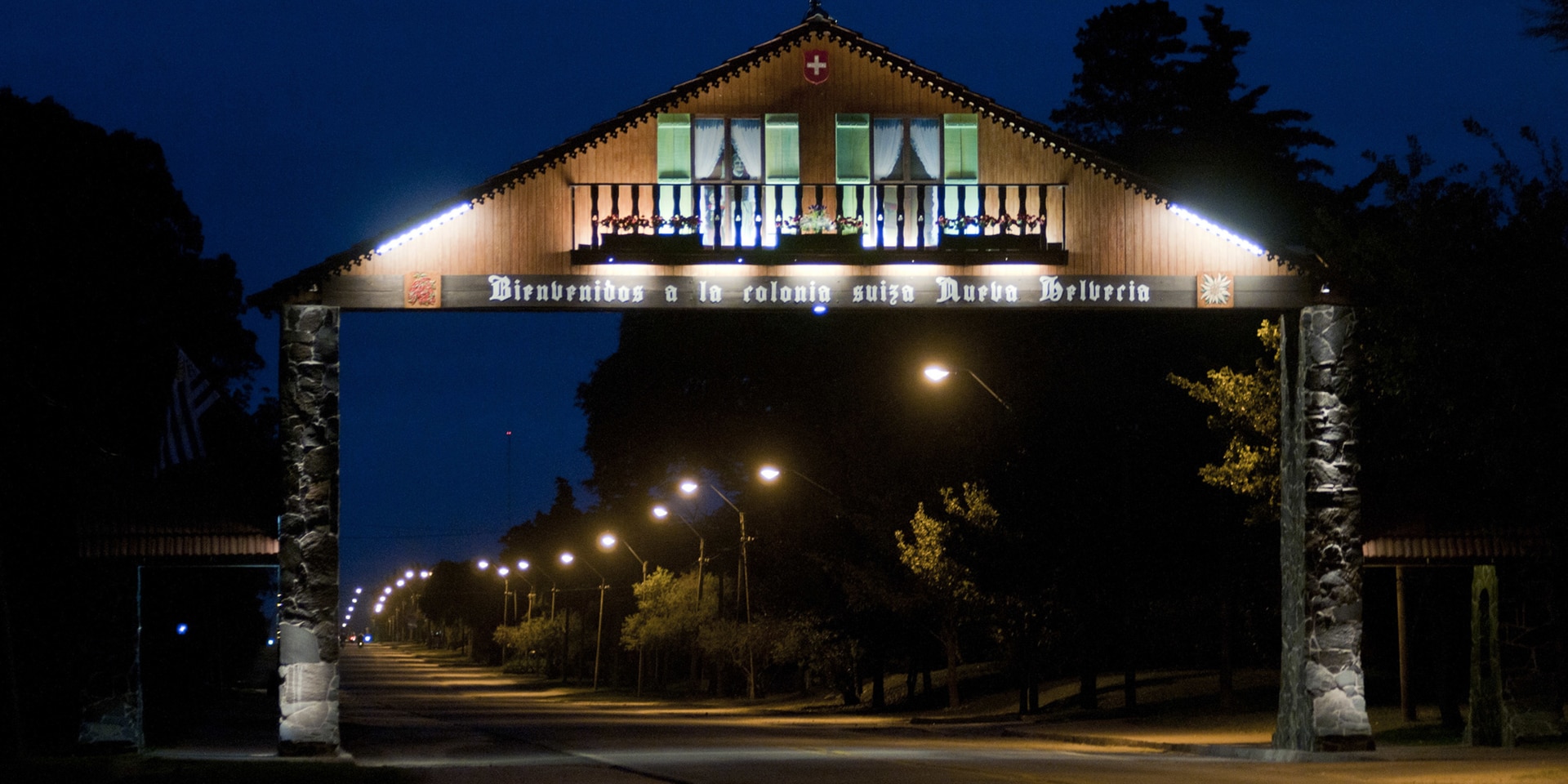 Un portique représentant un chalet aux motifs de la Suisse est disposé au-dessus d’une route, de nuit.