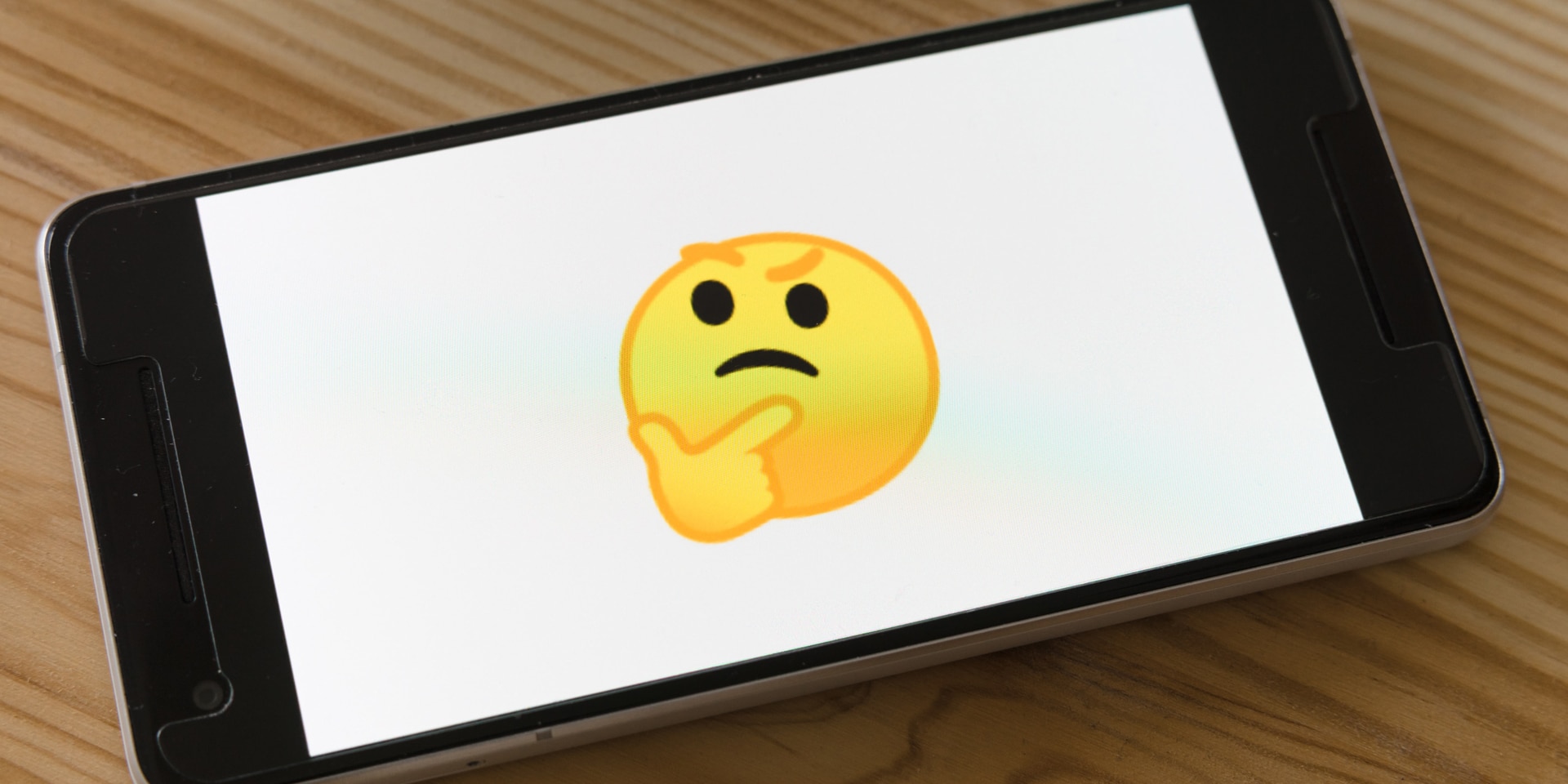 Ein Smartphone zeigt ein Emoji, das etwas hinterfragt.