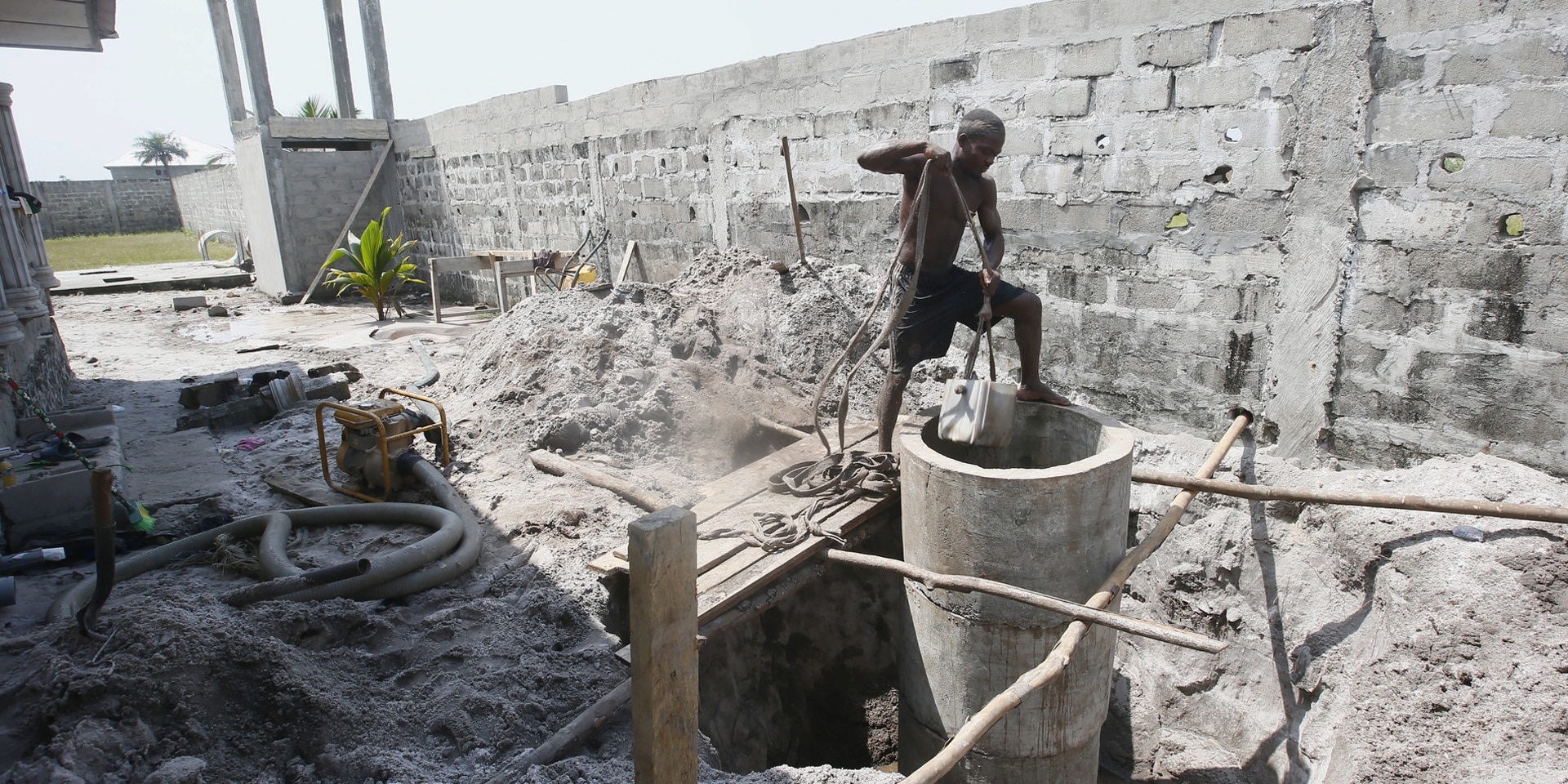 Un homme pellette de la terre sur le chantier d’un puits.