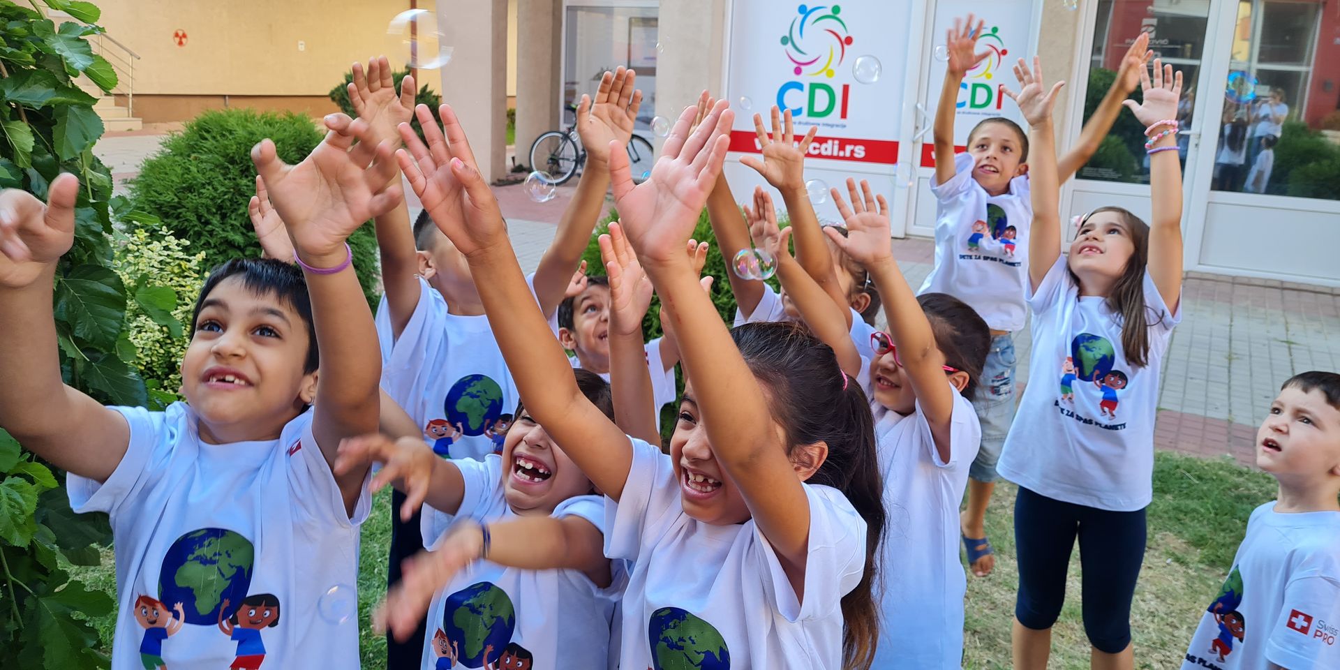 Un groupe d'enfant lève les mains en l'air et rit.